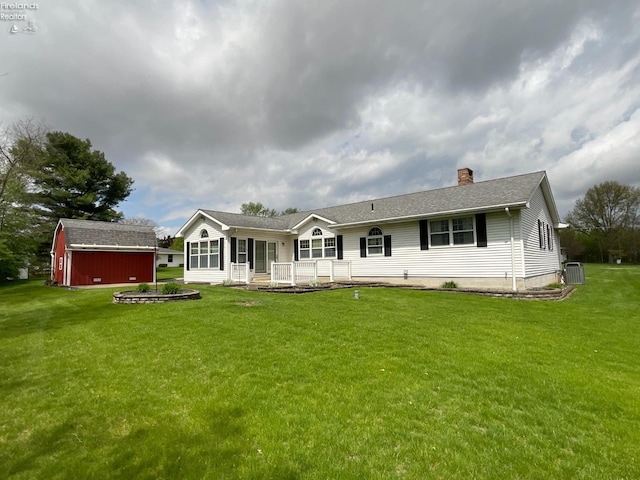back of house with a lawn, cooling unit, an outdoor structure, and a shed