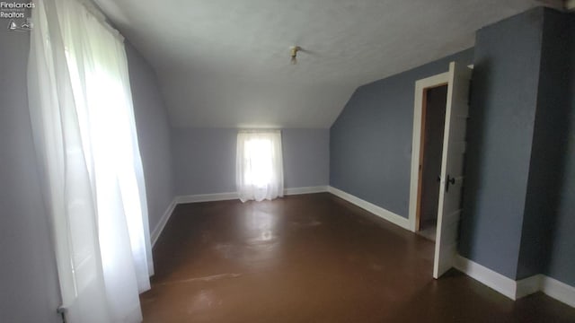 bonus room with finished concrete floors, baseboards, and vaulted ceiling