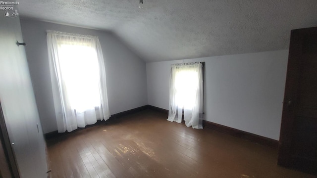 bonus room with wood-type flooring, a textured ceiling, lofted ceiling, and a healthy amount of sunlight