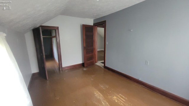 unfurnished bedroom with baseboards, a textured ceiling, and vaulted ceiling