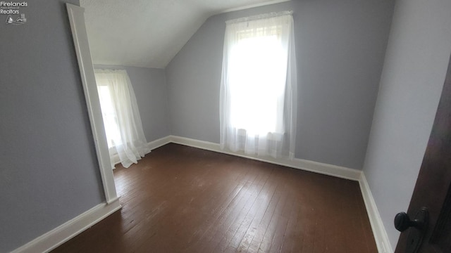 additional living space featuring baseboards, dark wood finished floors, and lofted ceiling