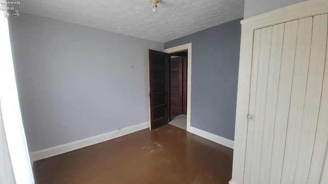 unfurnished bedroom featuring a closet, a textured ceiling, and baseboards
