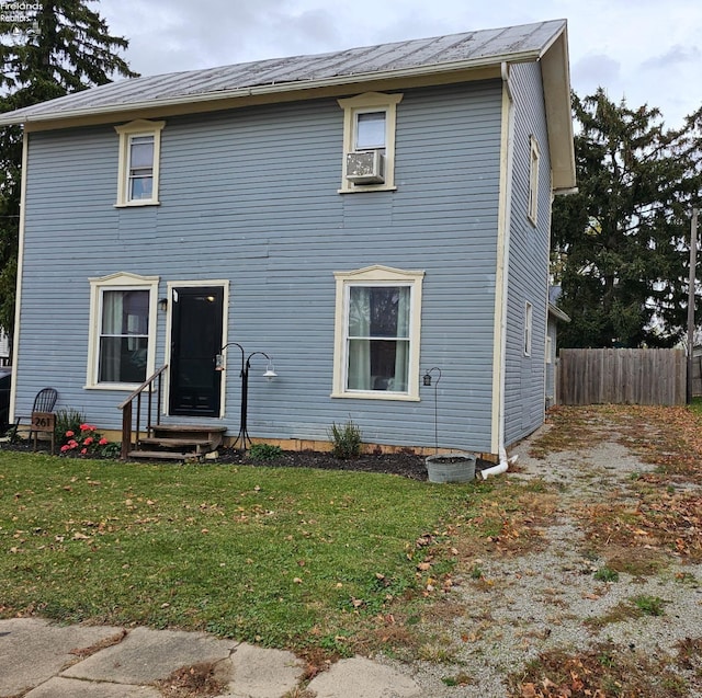 colonial-style house with fence, entry steps, and a front lawn