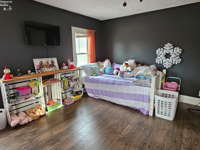 bedroom with a textured ceiling, baseboards, and wood finished floors