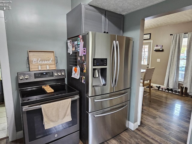 kitchen with appliances with stainless steel finishes, baseboards, dark wood finished floors, and a textured ceiling