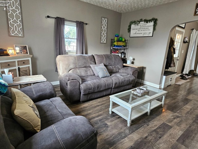 living room featuring baseboards, arched walkways, and wood finished floors