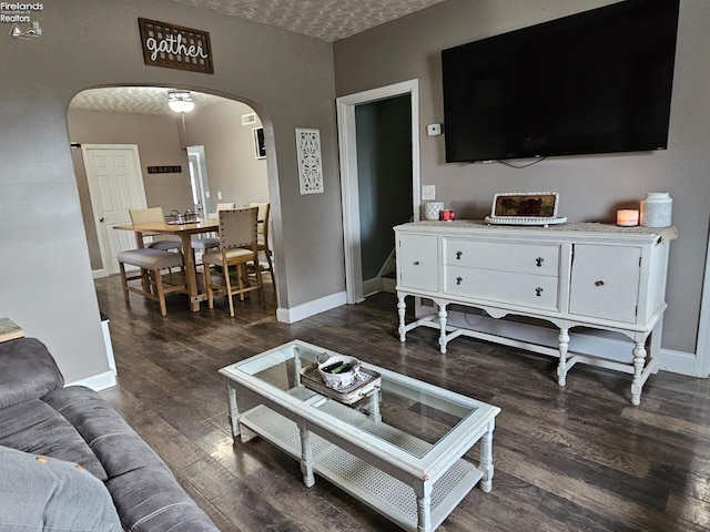 living area featuring dark wood-style flooring, arched walkways, and baseboards
