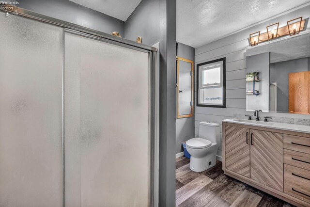 1733 County Road 302, Bellevue, OH 44811 - bathroom featuring wood finished floors, a stall shower, vanity, a textured ceiling, and toilet