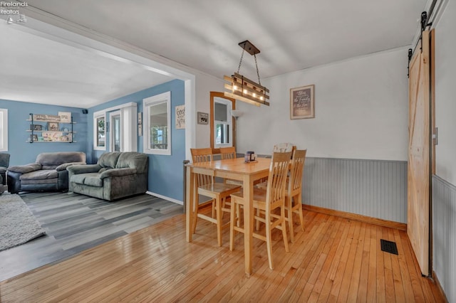 1733 County Road 302, Bellevue, OH 44811 - dining space with a barn door, light wood finished floors, and wainscoting