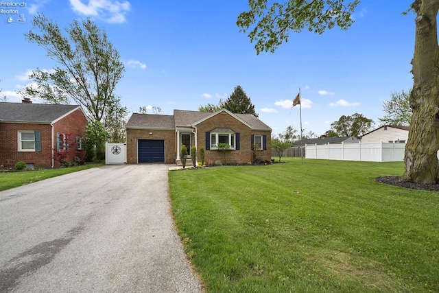 ranch-style house featuring a front lawn, aphalt driveway, fence, brick siding, and an attached garage
