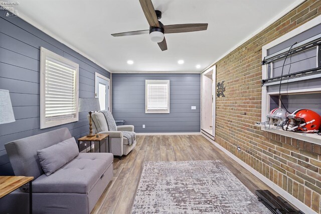 sitting room with baseboards, ceiling fan, brick wall, and hardwood / wood-style flooring