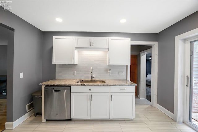 kitchen with a sink, dishwasher, baseboards, backsplash, and visible vents