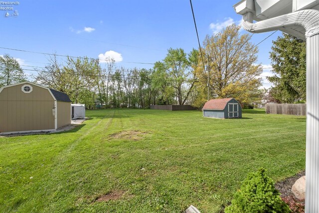 view of yard with a storage shed, fence, and an outdoor structure