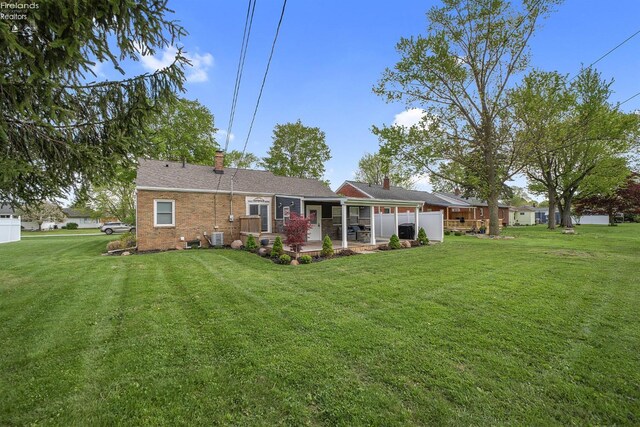 rear view of property featuring brick siding, a lawn, a chimney, and a patio