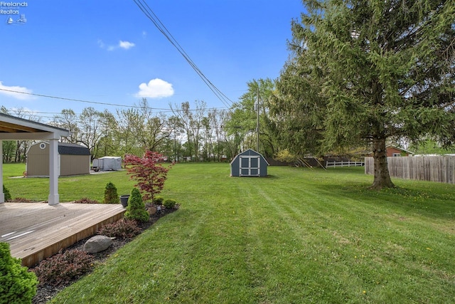 view of yard featuring fence, an outbuilding, a shed, and a wooden deck