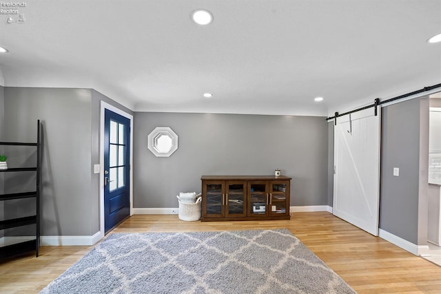 entrance foyer featuring baseboards, light wood-style flooring, recessed lighting, and a barn door
