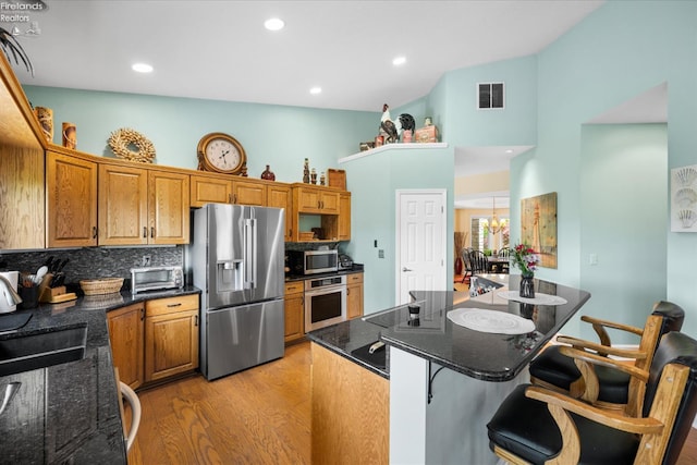 3535 E High Point Ln, Port Clinton, OH 43452 - kitchen featuring stainless steel appliances, light wood-type flooring, a kitchen bar, a kitchen island, and high vaulted ceiling