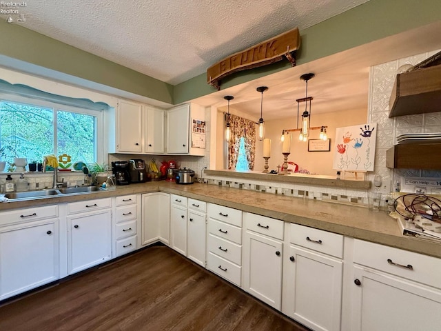 kitchen with white cabinets, backsplash, dark wood finished floors, and a sink