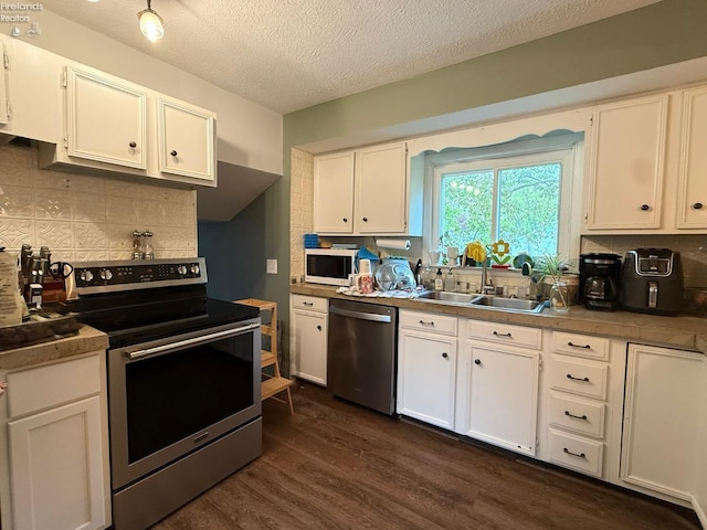 kitchen with white cabinetry, appliances with stainless steel finishes, dark wood-type flooring, and tasteful backsplash