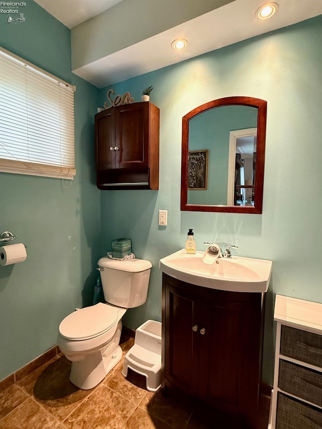 half bathroom with vanity, recessed lighting, baseboards, and toilet