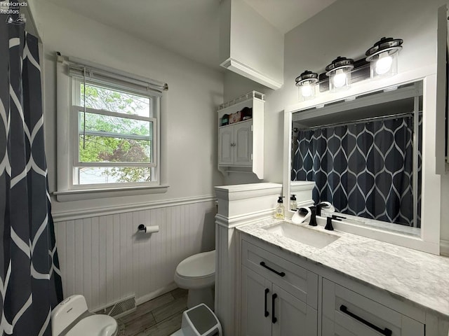 full bath with vanity, wood finished floors, toilet, a wainscoted wall, and a shower with curtain