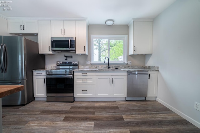 5033 Crestline Rd, Bucyrus, OH 44820 - kitchen featuring dark wood-style flooring, light stone counters, a sink, white cabinetry, and appliances with stainless steel finishes