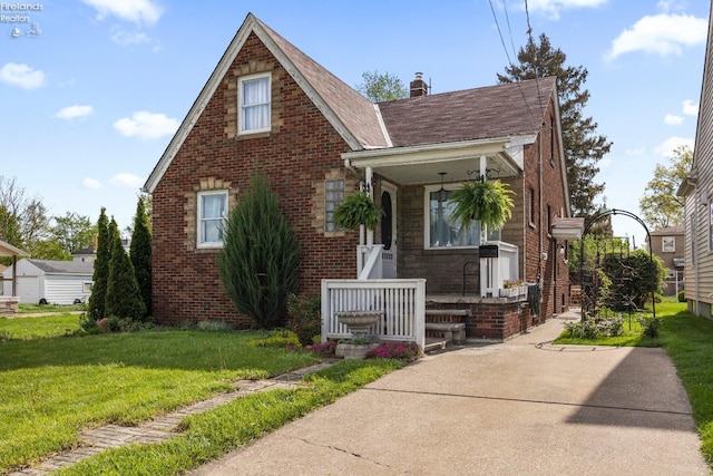 view of front of home featuring a chimney, brick siding, and a front yard