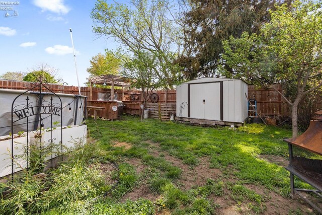 view of yard featuring an outdoor structure, a fenced backyard, and a storage unit