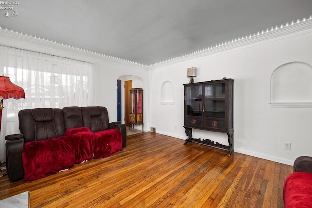 living area featuring arched walkways, baseboards, and wood finished floors