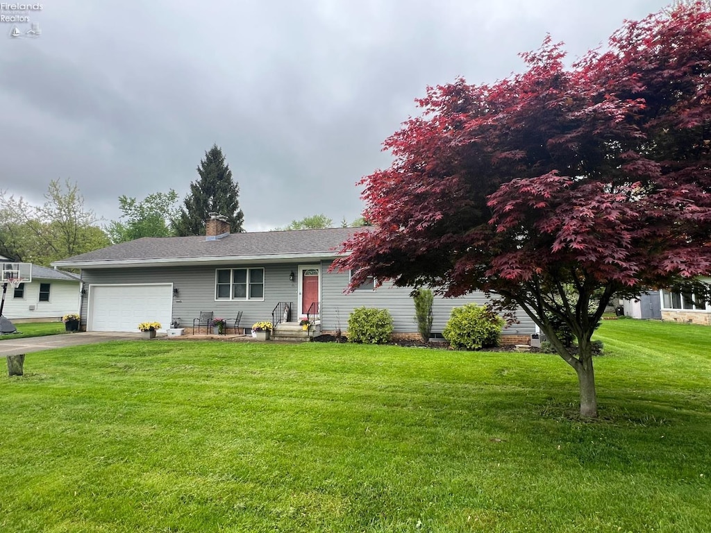 view of front of property featuring driveway, an attached garage, a chimney, and a front yard