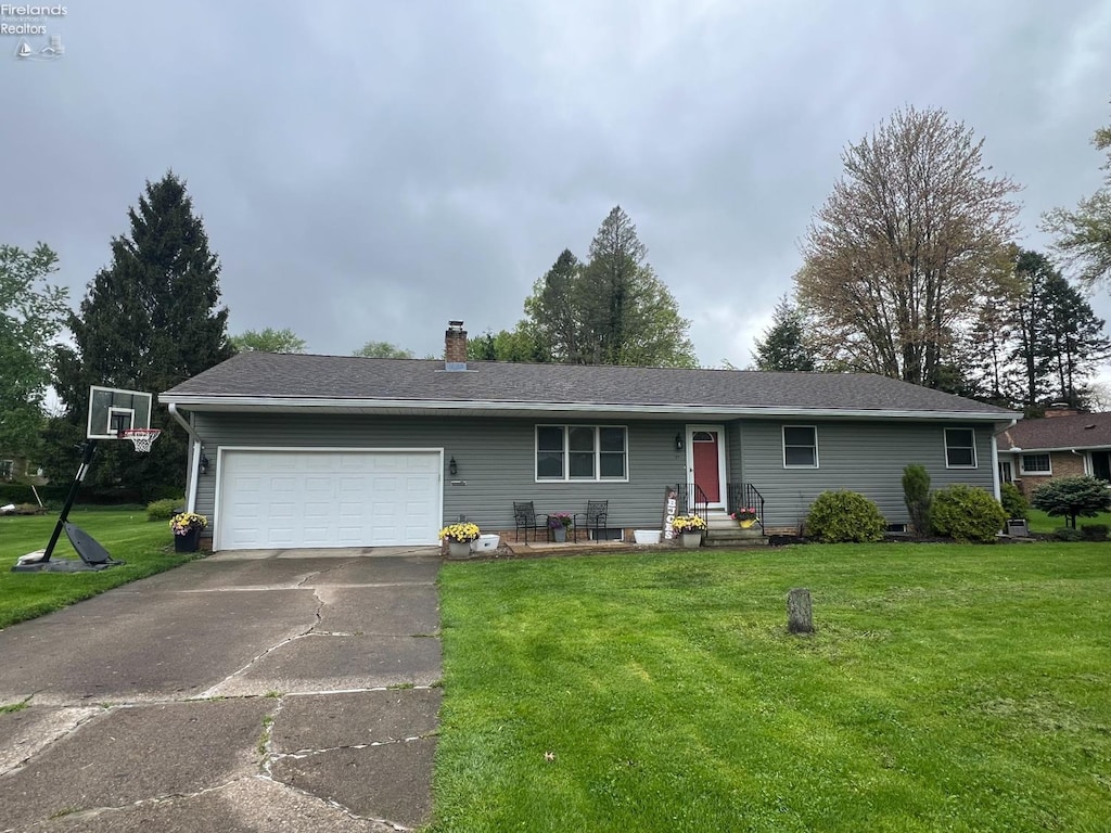 ranch-style home featuring a chimney, a front lawn, a garage, and concrete driveway