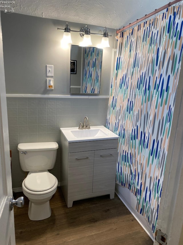 604 E Jefferson St, Sandusky, OH 44870 - bathroom with wood finished floors, toilet, vanity, a textured ceiling, and tile walls
