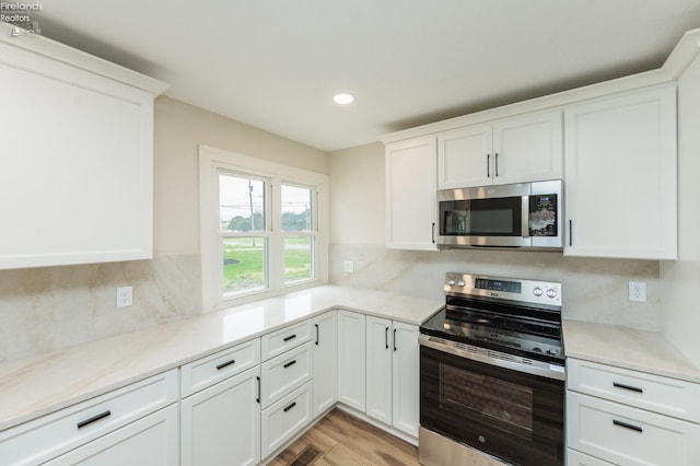412 E 10th St, Port Clinton, OH 43452 - kitchen with stainless steel appliances, recessed lighting, white cabinets, decorative backsplash, and light wood-style floors