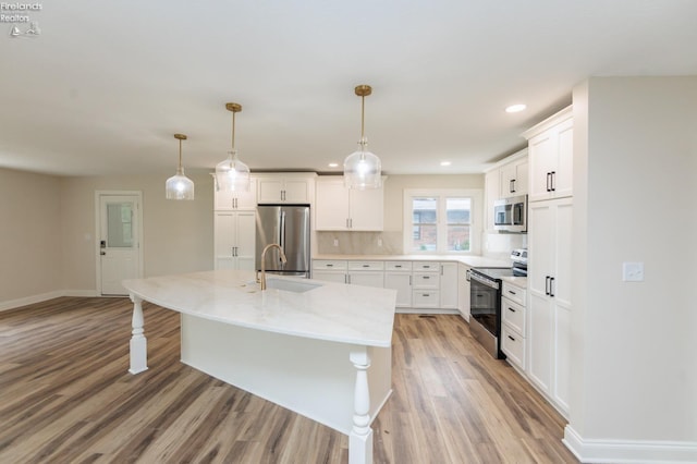 412 E 10th St, Port Clinton, OH 43452 - kitchen with appliances with stainless steel finishes, light wood finished floors, white cabinets, a sink, and light stone counters