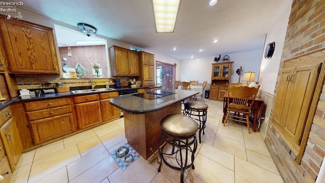 66 Hillcrest Dr, Willard, OH 44890 - kitchen with a sink, brown cabinetry, a kitchen breakfast bar, a kitchen island, and dark countertops