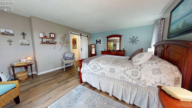 66 Hillcrest Dr, Willard, OH 44890 - bedroom featuring wood finished floors, a barn door, and baseboards