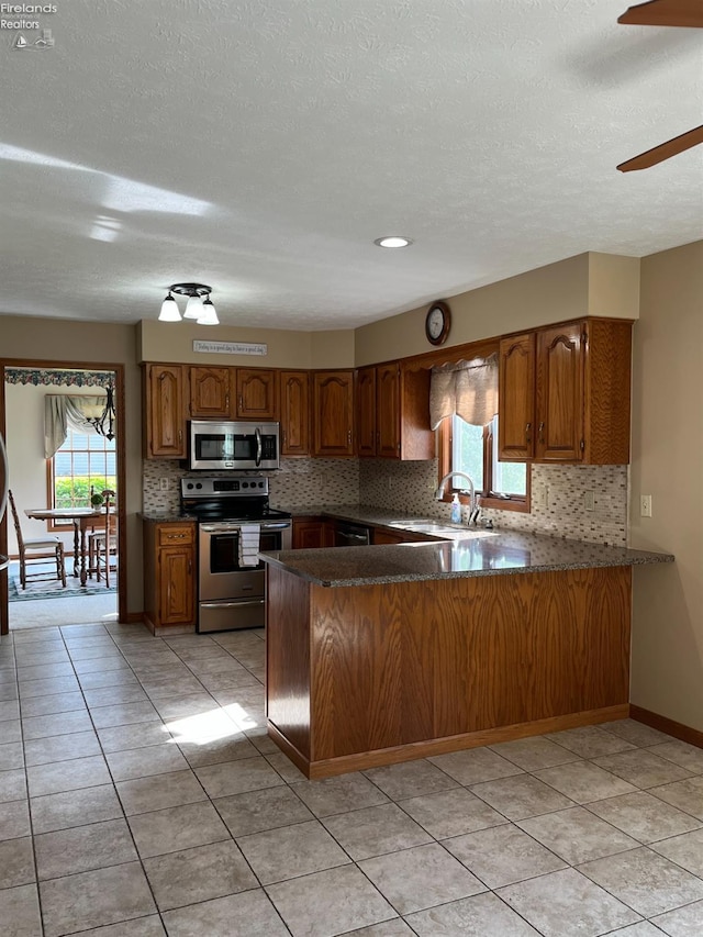 378 Lelar St, Tiffin, OH 44883 - kitchen featuring appliances with stainless steel finishes, brown cabinets, a sink, a peninsula, and a textured ceiling