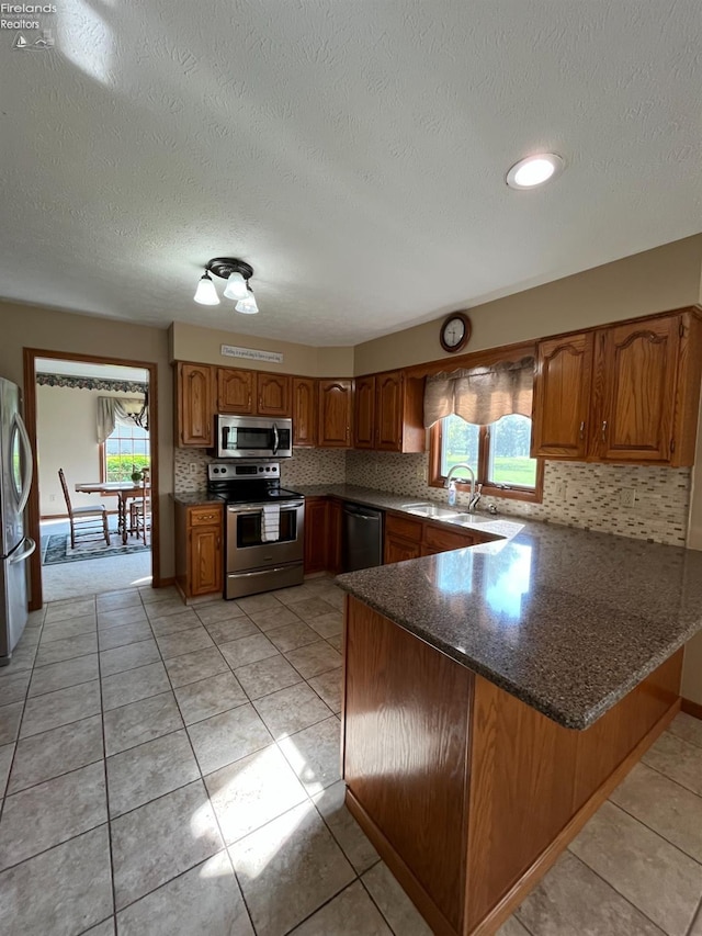378 Lelar St, Tiffin, OH 44883 - kitchen with appliances with stainless steel finishes, a peninsula, a sink, brown cabinets, and tasteful backsplash