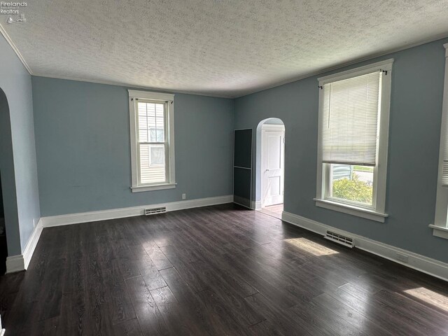 515 W Osborne St, Sandusky, OH 44870 - empty room with arched walkways, a textured ceiling, dark wood finished floors, and baseboards