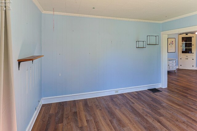 unfurnished room featuring wood finished floors, baseboards, and crown molding