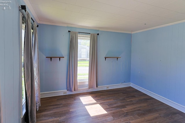 empty room with ornamental molding, dark wood-style flooring, and baseboards