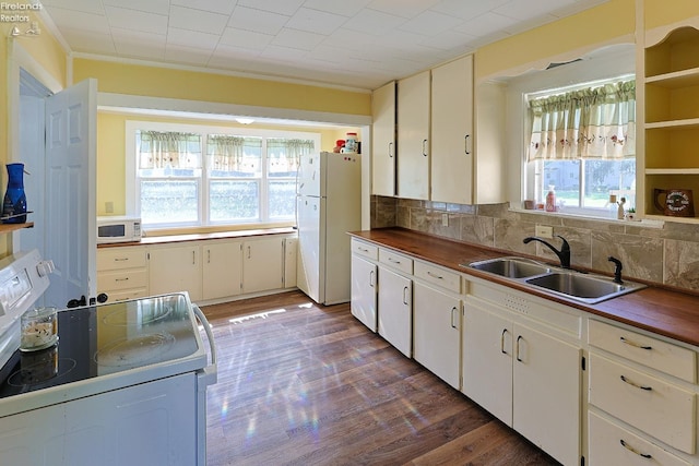 kitchen featuring white appliances, a sink, tasteful backsplash, dark wood finished floors, and white cabinets