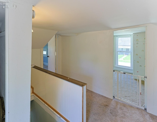hallway with carpet floors and an upstairs landing