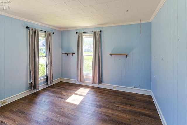 empty room featuring crown molding, wood finished floors, and baseboards