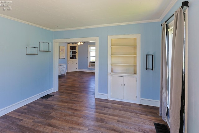 unfurnished room with crown molding, dark wood-style flooring, baseboards, built in features, and ceiling fan