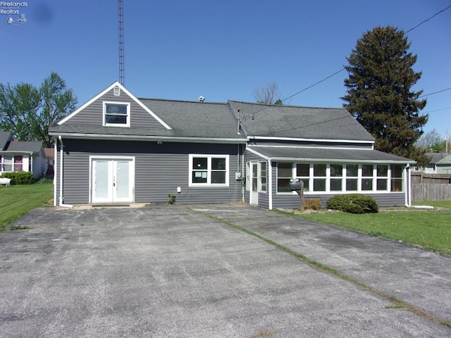 417 Race St, Clyde, OH 43410 - rear view of property with french doors, a sunroom, a lawn, roof with shingles, and driveway