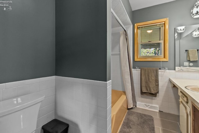 bathroom with tile walls, tile patterned flooring, vanity, wainscoting, and toilet
