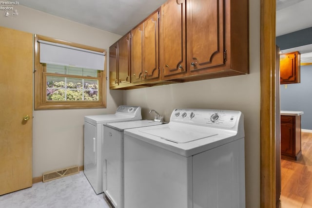 clothes washing area with washer and clothes dryer, cabinet space, and baseboards
