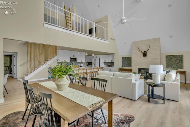 1861 N Opfer Lentz Rd, Martin, OH 43445 - dining room featuring high vaulted ceiling, light wood finished floors, stairway, a ceiling fan, and a large fireplace