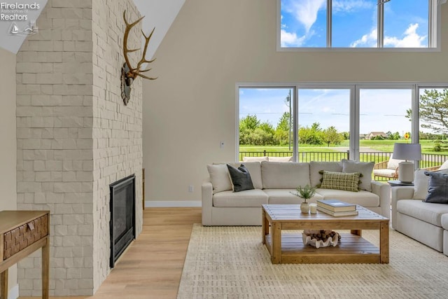 1861 N Opfer Lentz Rd, Martin, OH 43445 - living room featuring high vaulted ceiling, light wood finished floors, plenty of natural light, a brick fireplace, and baseboards